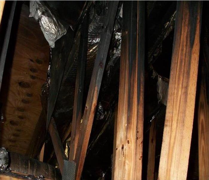 attic space with charred trusses and falling foil