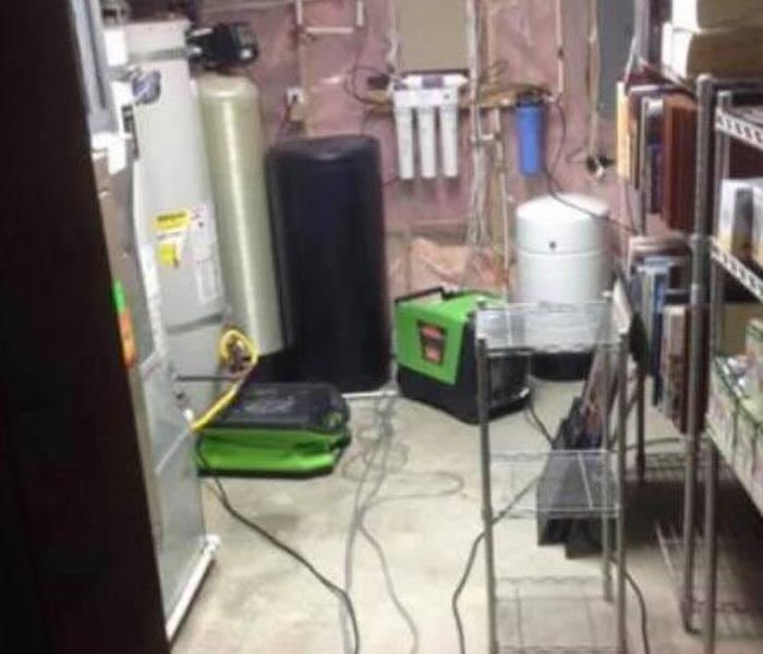 Image of 2 servpro equipment pieces drying an area next to a hot water heater